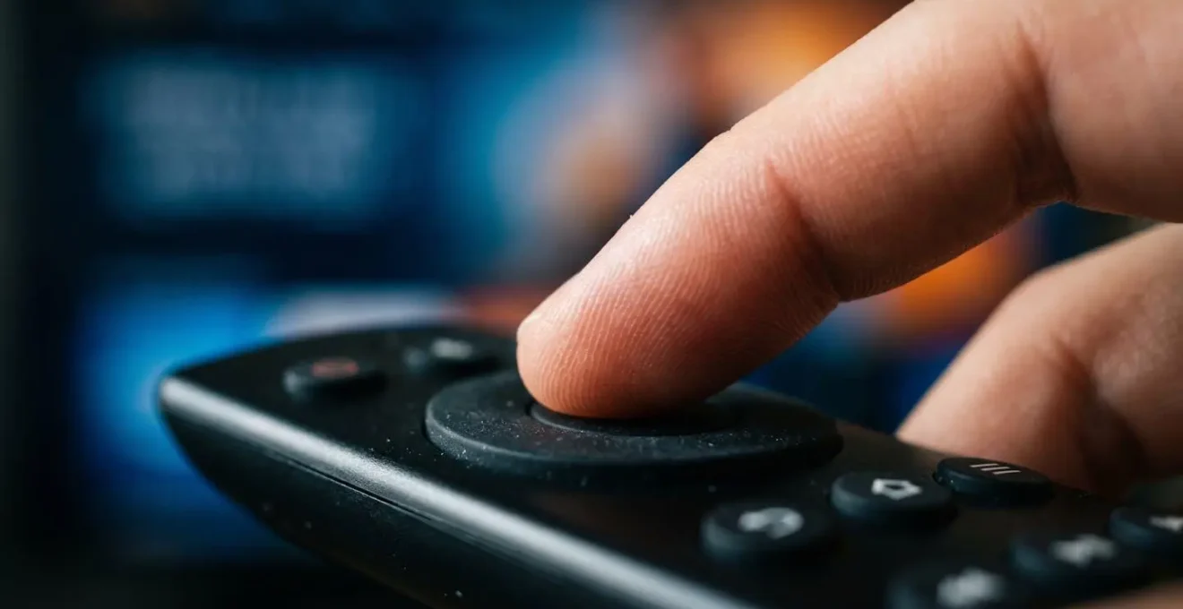 Primo piano macro di dito che preme pulsante pausa su telecomando