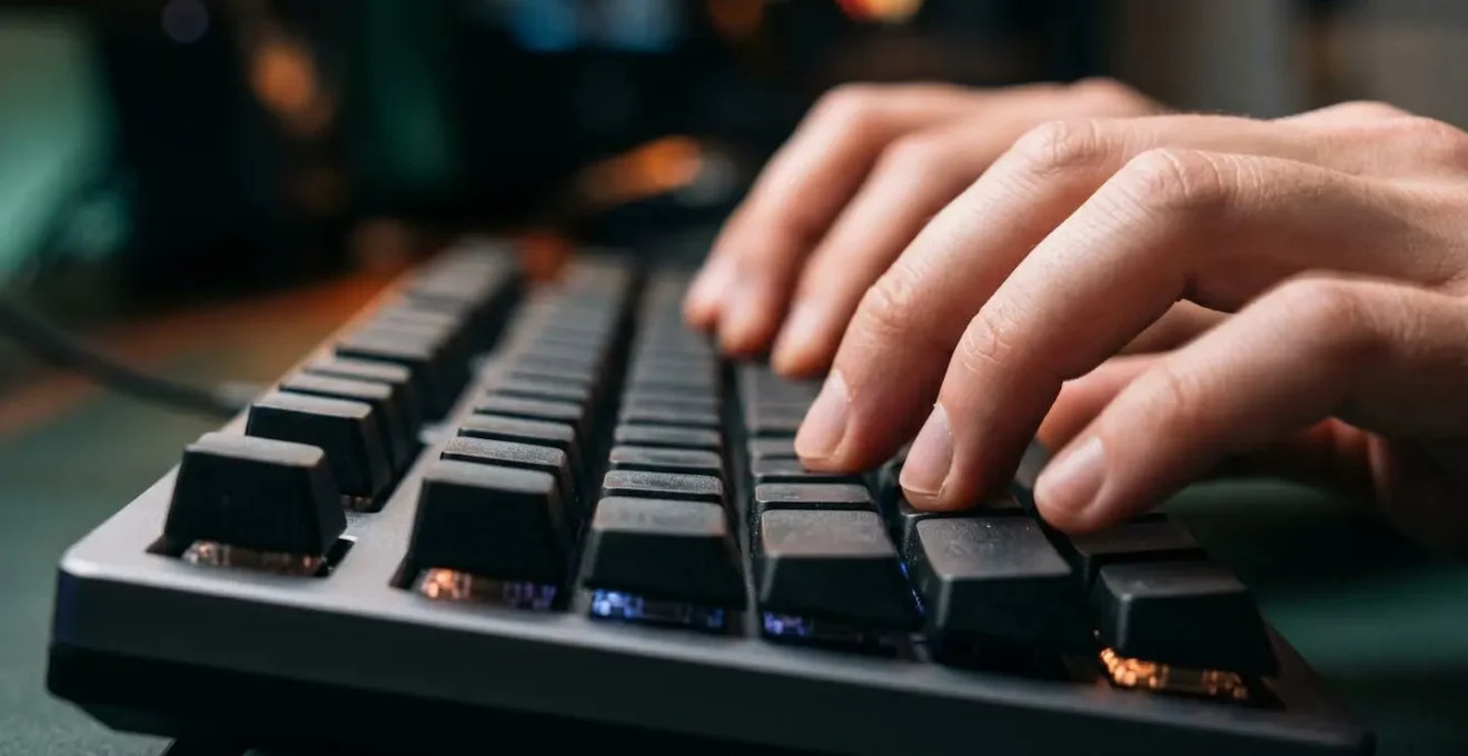 Primo piano macro di mani che digitano su tastiera meccanica con riflessi luminosi astratti